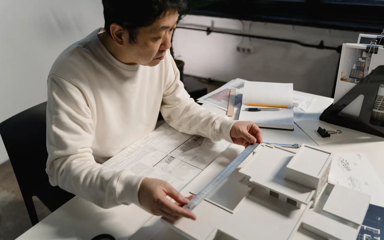 Ontwerper aan een bureau met tekeningen en maquettes