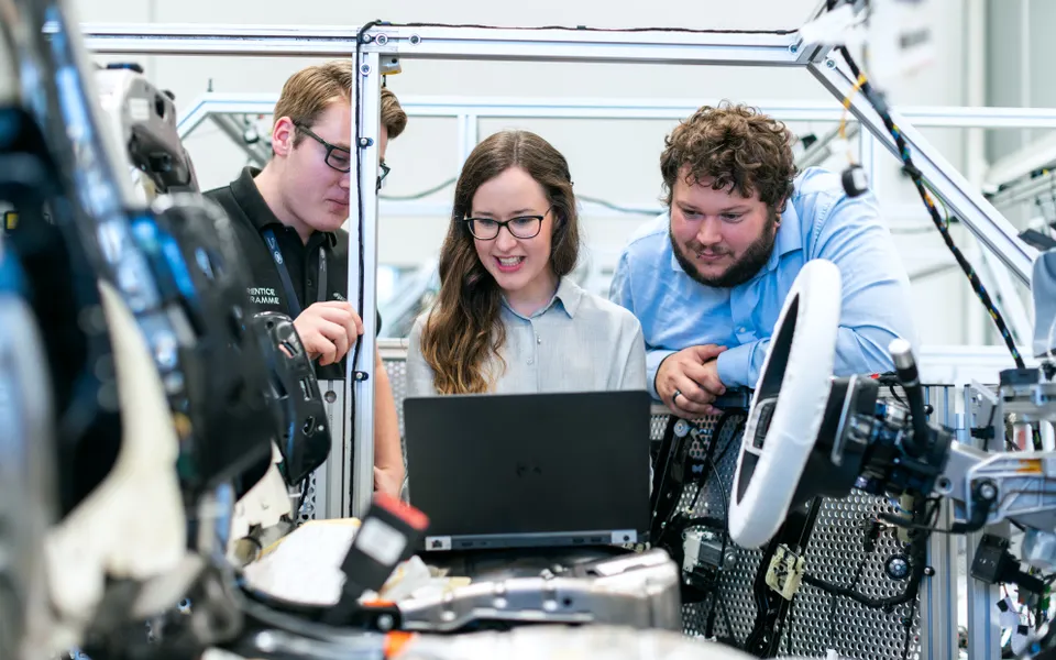 Technicians discussing beside a vehicle in a workshop